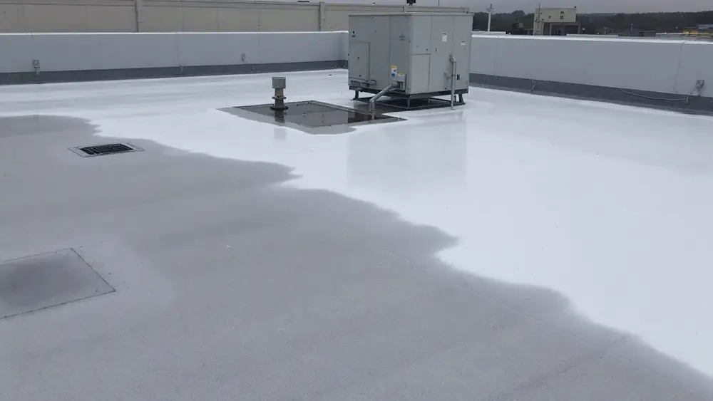 Ponded water near a roof drain on a single-ply commercial roof beside a rooftop HVAC unit