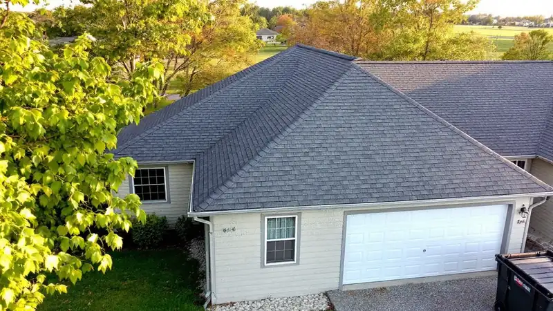 House roof mid-replacement with half the deck stripped and half covered in new architectural shingles