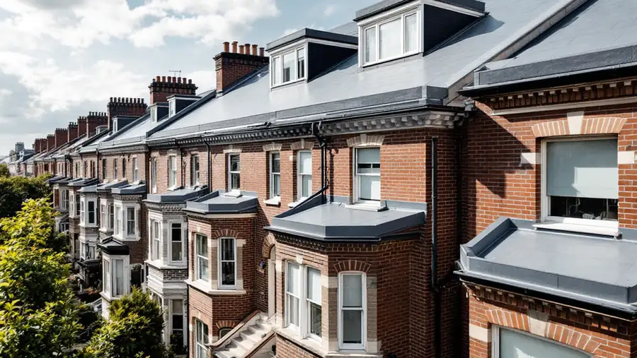 Attached brick rowhouses with flat membrane roofs and parapet walls in a New York City neighborhood